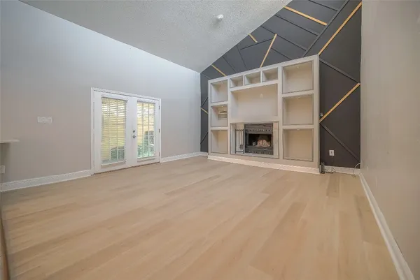 an empty room with fireplace cabinet and windows