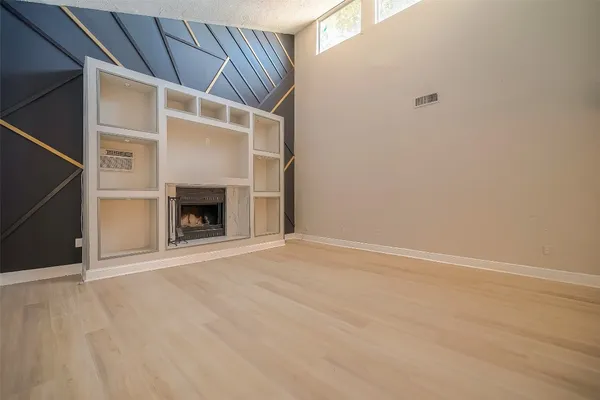 an empty room with wooden floor and fireplace