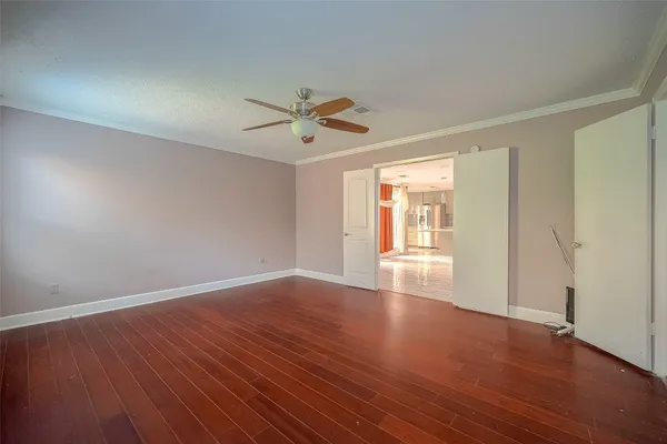 a view of empty room with wooden floor and fan