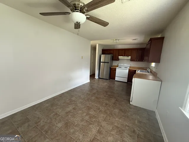 an empty room with fireplace and ceiling fan
