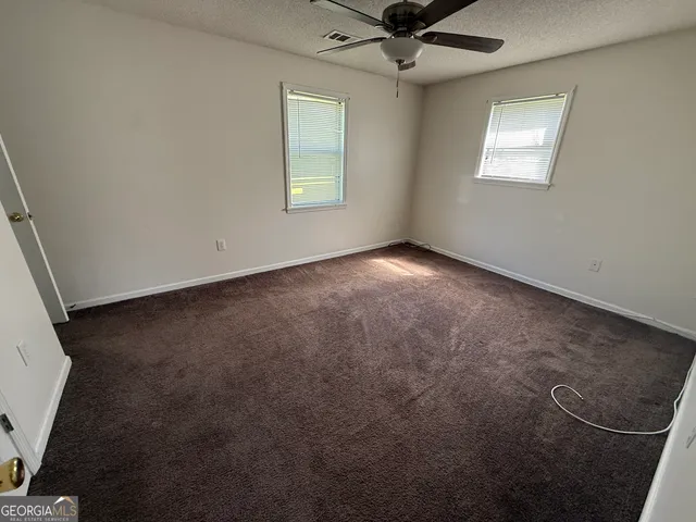 an empty room with a window and a fan