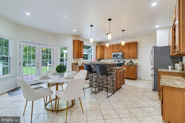 a kitchen with stainless steel appliances granite countertop a stove a sink a microwave a dining table and chairs