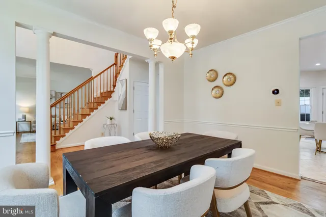 a dining room with wooden floor a chandelier a wooden table and chairs