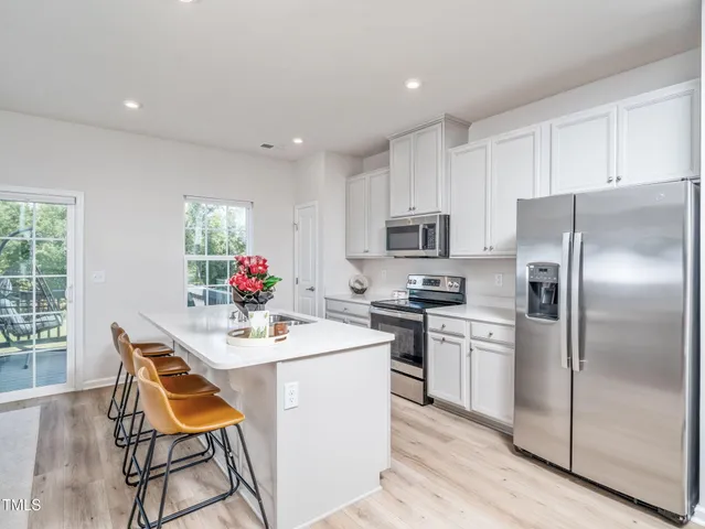 a kitchen with stainless steel appliances kitchen island granite countertop a sink refrigerator and microwave
