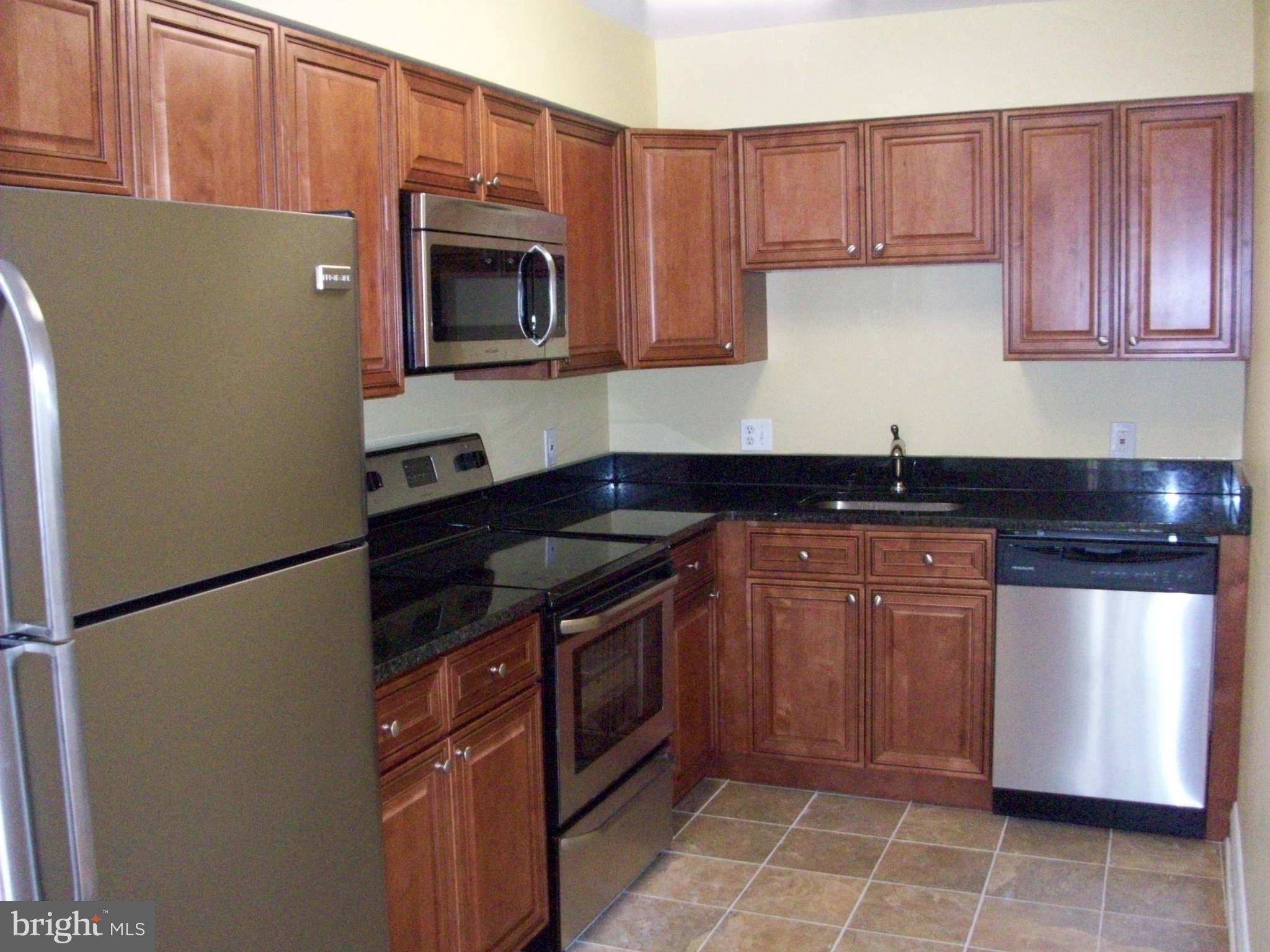 3105 Berry Road Northeast, Unit 11 Washington, DC 20018 - Photo 4 of 8 a kitchen with granite countertop a stove and a microwave
