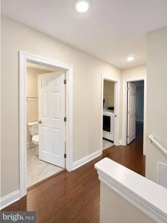 a view of a hallway with wooden floor and cabinet