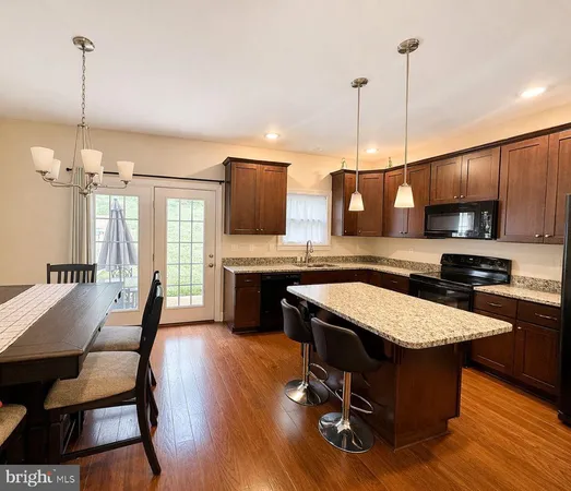 a kitchen with kitchen island granite countertop wooden floors and a view of living room