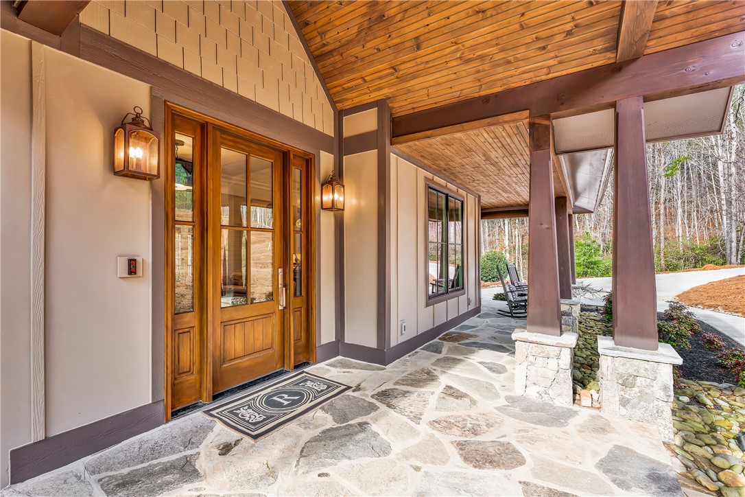 243 Quay Court Sunset, SC 29685 - Photo 5 of 46 This inviting covered entry features stone flooring and exposed wood beams, creating a harmonious blend of natural elements.