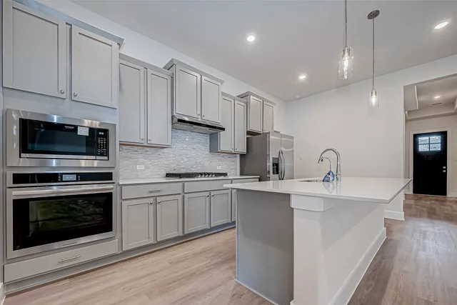 a kitchen with stainless steel appliances granite countertop a sink stove and microwave with wooden floor