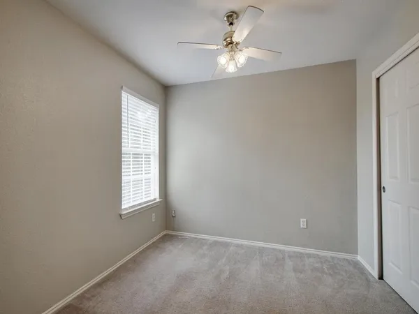 an empty room with windows and fan