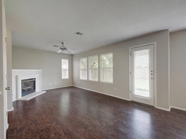 an empty room with wooden floor fireplace and windows
