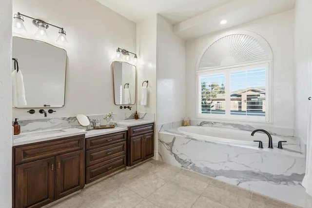 a spacious bathroom with a tub sink and mirror