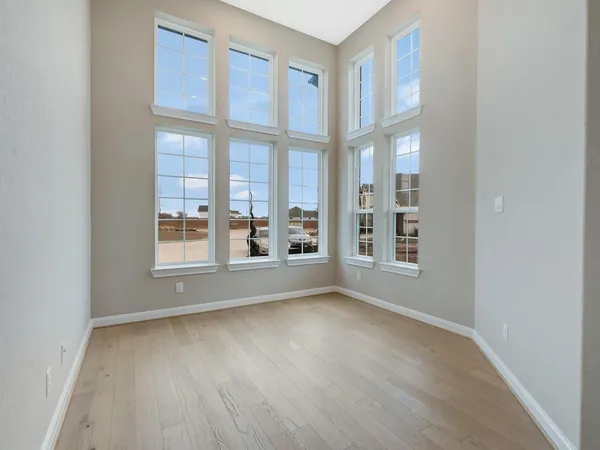 a view of an empty room with a window and wooden floor