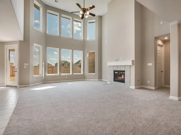 a view of an empty room with a fireplace and a ceiling fan