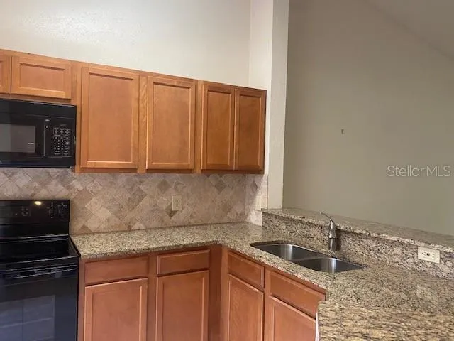 a kitchen with granite countertop a sink stove and cabinets