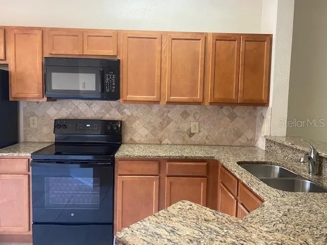 a kitchen with granite countertop a sink and a stove