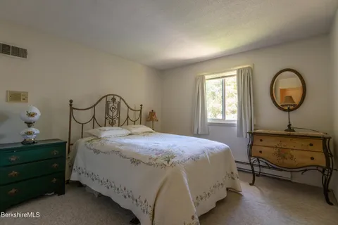 a bedroom with a bed a dresser and window