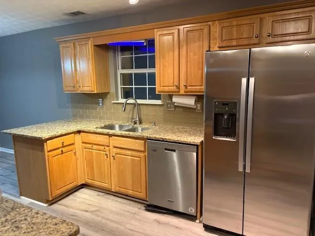 a kitchen with stainless steel appliances granite countertop a refrigerator and a sink