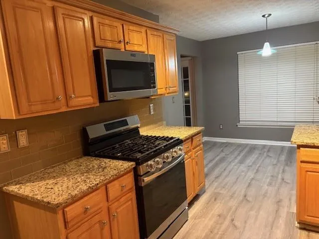 a kitchen with granite countertop a stove and a microwave
