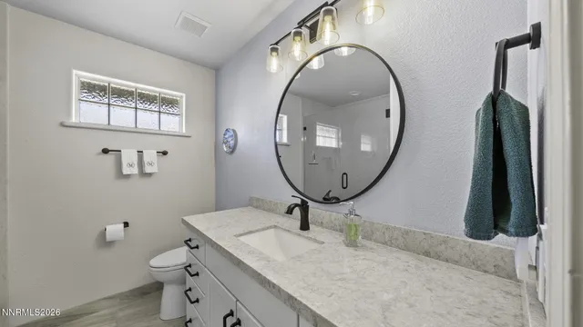 a bathroom with a granite countertop toilet a sink and a mirror