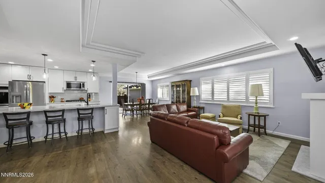 a living room with furniture kitchen area and a wooden floor