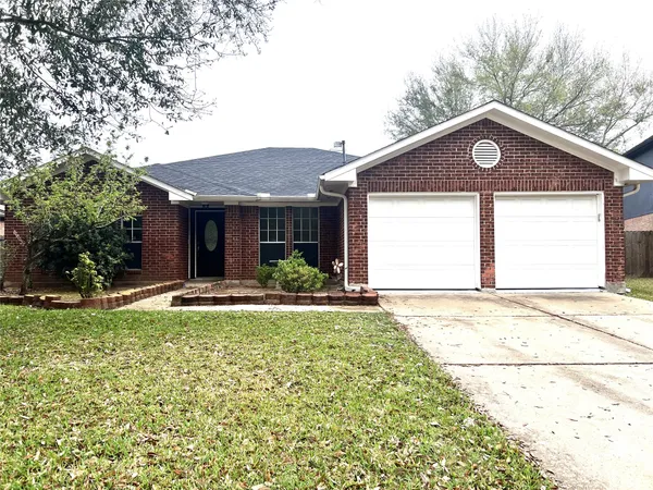 a view of a house with a yard plants and large tree