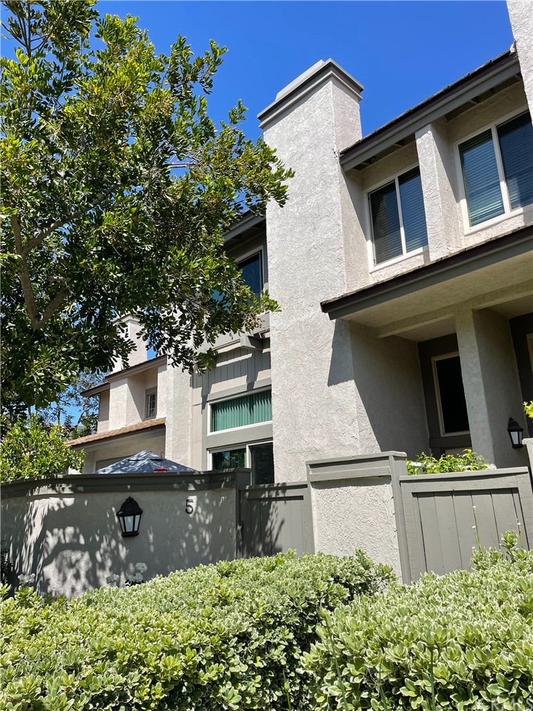 a view of a house with a small yard plants and large tree
