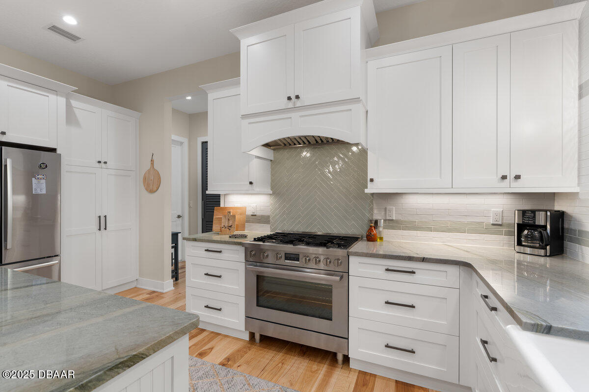 54 Ocean Way Drive Ponce Inlet, FL 32127 - Photo 16 of 76 a kitchen with granite countertop white cabinets and stainless steel appliances