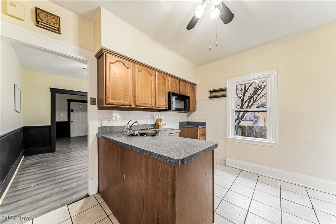 2014 Cook Avenue Cleveland, OH 44109 - Photo 9 of 37 Kitchen with light tile patterned flooring, sink, ceiling fan, and kitchen peninsula