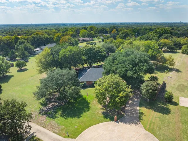an aerial view of residential houses with outdoor space and trees all around