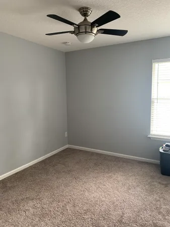 an empty room with a window and a fan