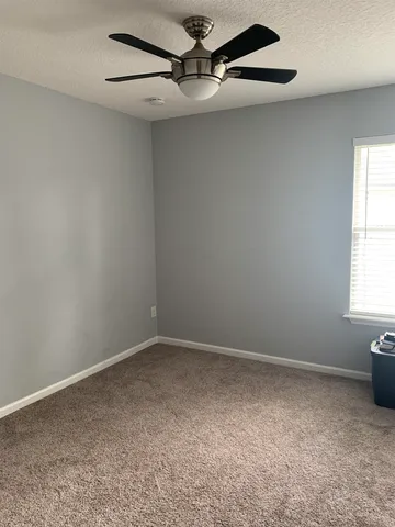 an empty room with a window and a fan