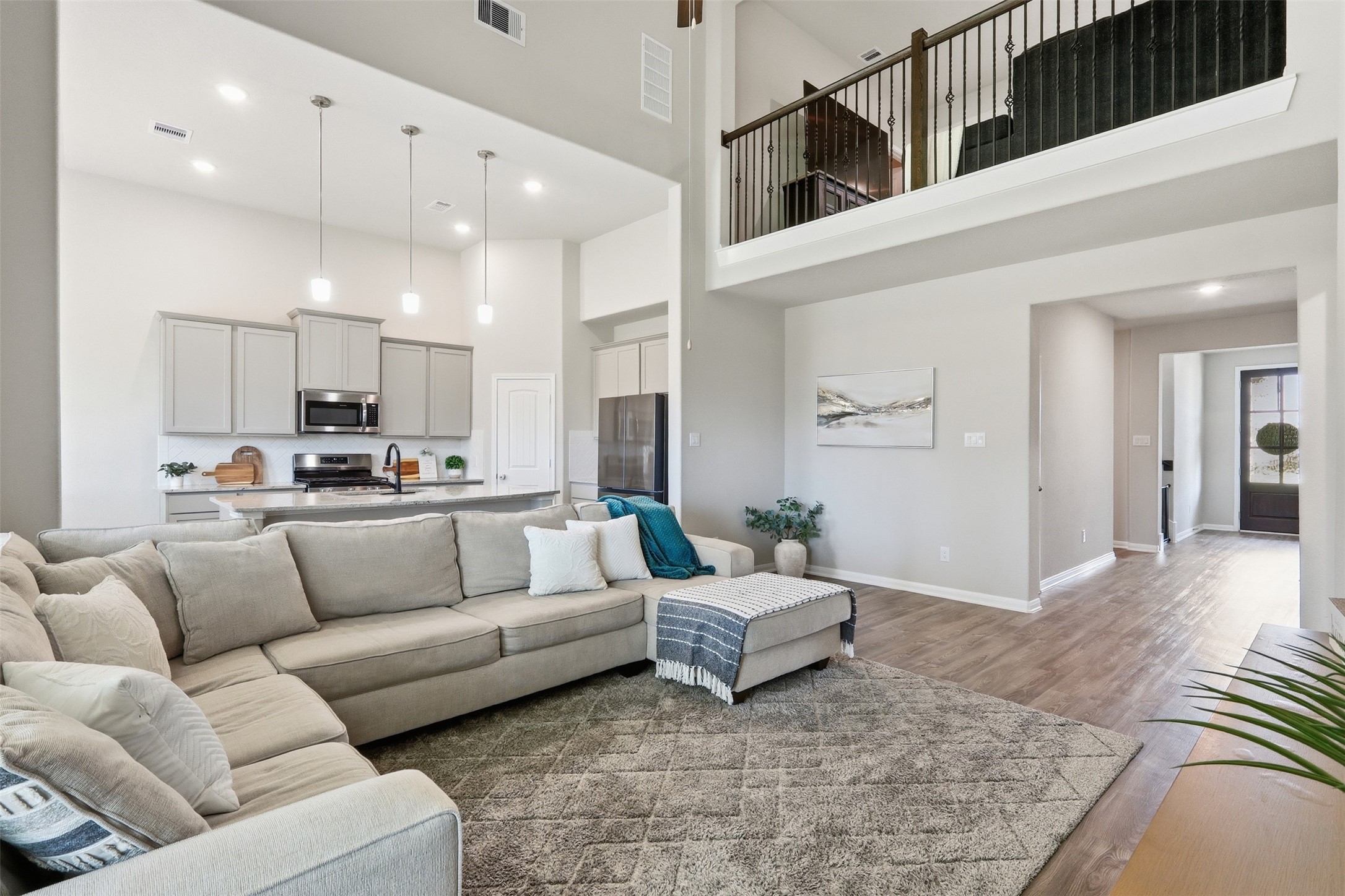 6310 Fawn Path Drive Conroe, TX 77303 - Photo 14 of 41 Open-concept living and kitchen area featuring soaring ceilings, stainless steel appliances, pendant lighting, abundant natural light, and views of the upstairs game room.