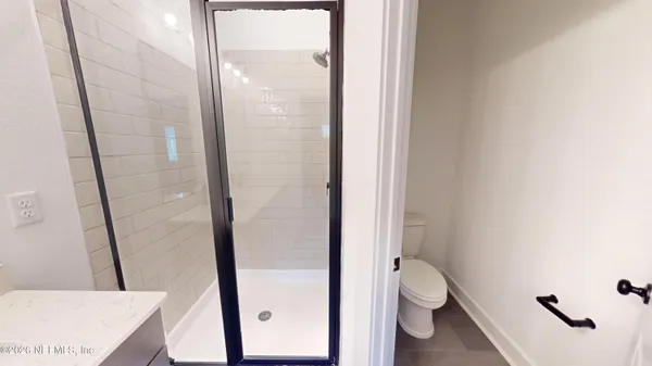 a bathroom with a granite countertop shower and a toilet