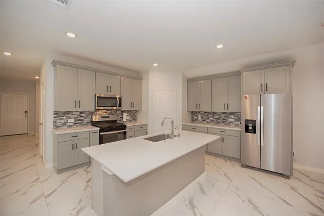 a kitchen with a refrigerator a stove top oven a sink and cabinets