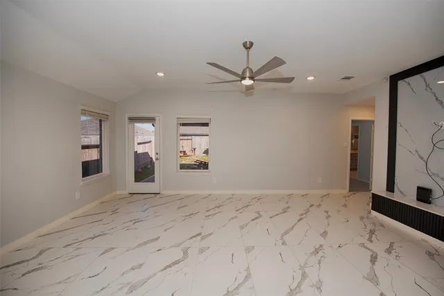 an empty room with windows and ceiling fan