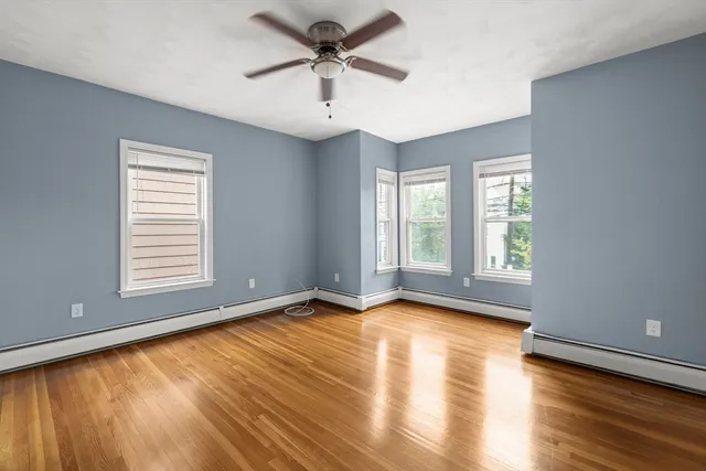 a view of an empty room with a window and wooden floor