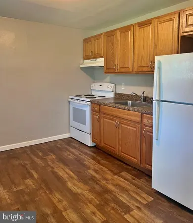 a kitchen with granite countertop a refrigerator sink and cabinets