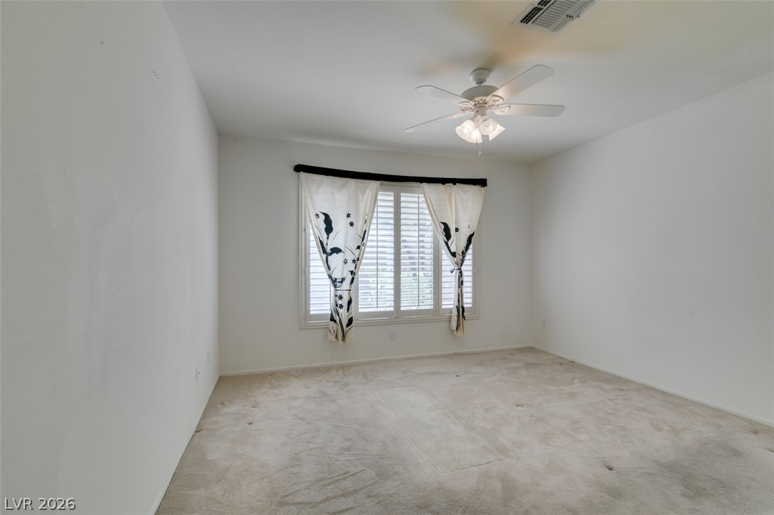 2189 Chapman Ranch Drive Henderson, NV 89012 - Photo 35 of 60 An arched window with integrated plantation shutters anchors this carpeted bedroom space.