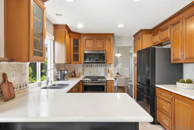 a kitchen with granite countertop a refrigerator a stove a sink a oven with wooden cabinets and floor