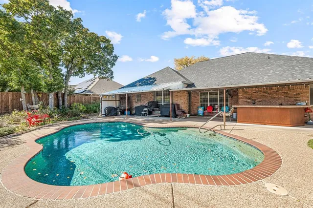 a view of a swimming pool with a patio and plants