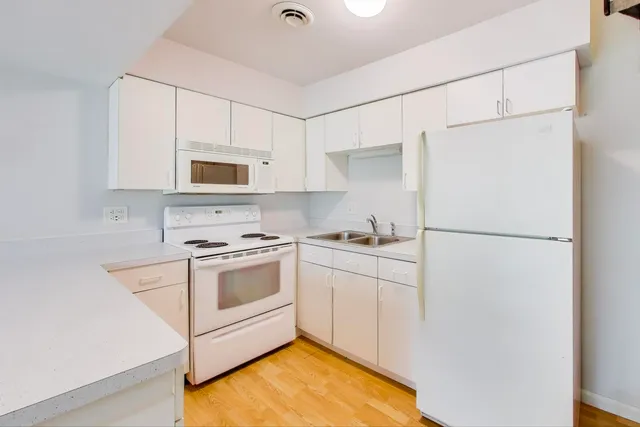 a kitchen with white cabinets and white appliances