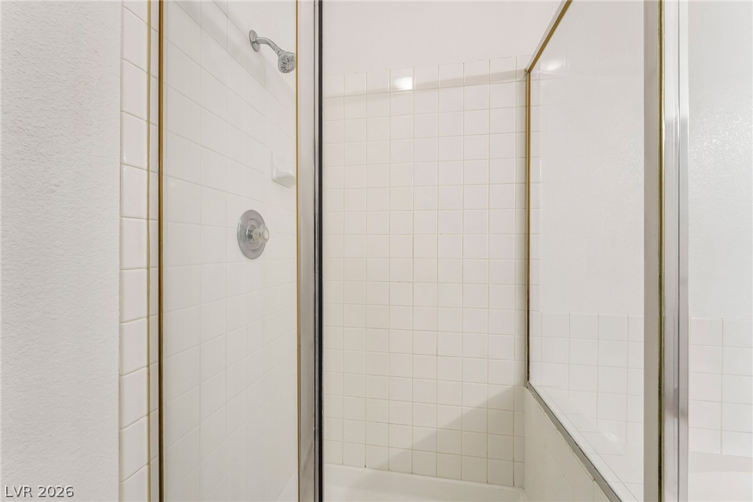 2201 Ramsgate Drive, Unit 811 Henderson, NV 89074 - Photo 26 of 36 White subway tiles line the bright shower enclosure, featuring a sleek glass door and modern shower head.