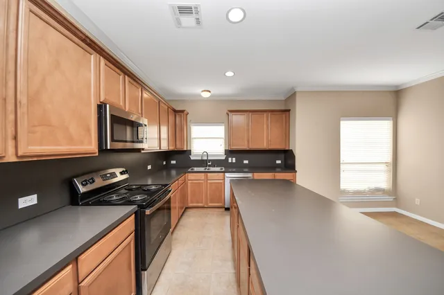 a kitchen with stainless steel appliances a stove a sink dishwasher a stove and a refrigerator with wooden floor