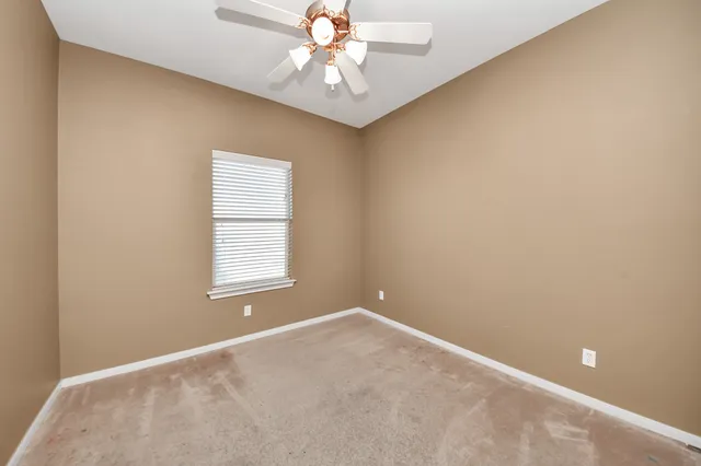 an empty room with chandelier fan and closet area