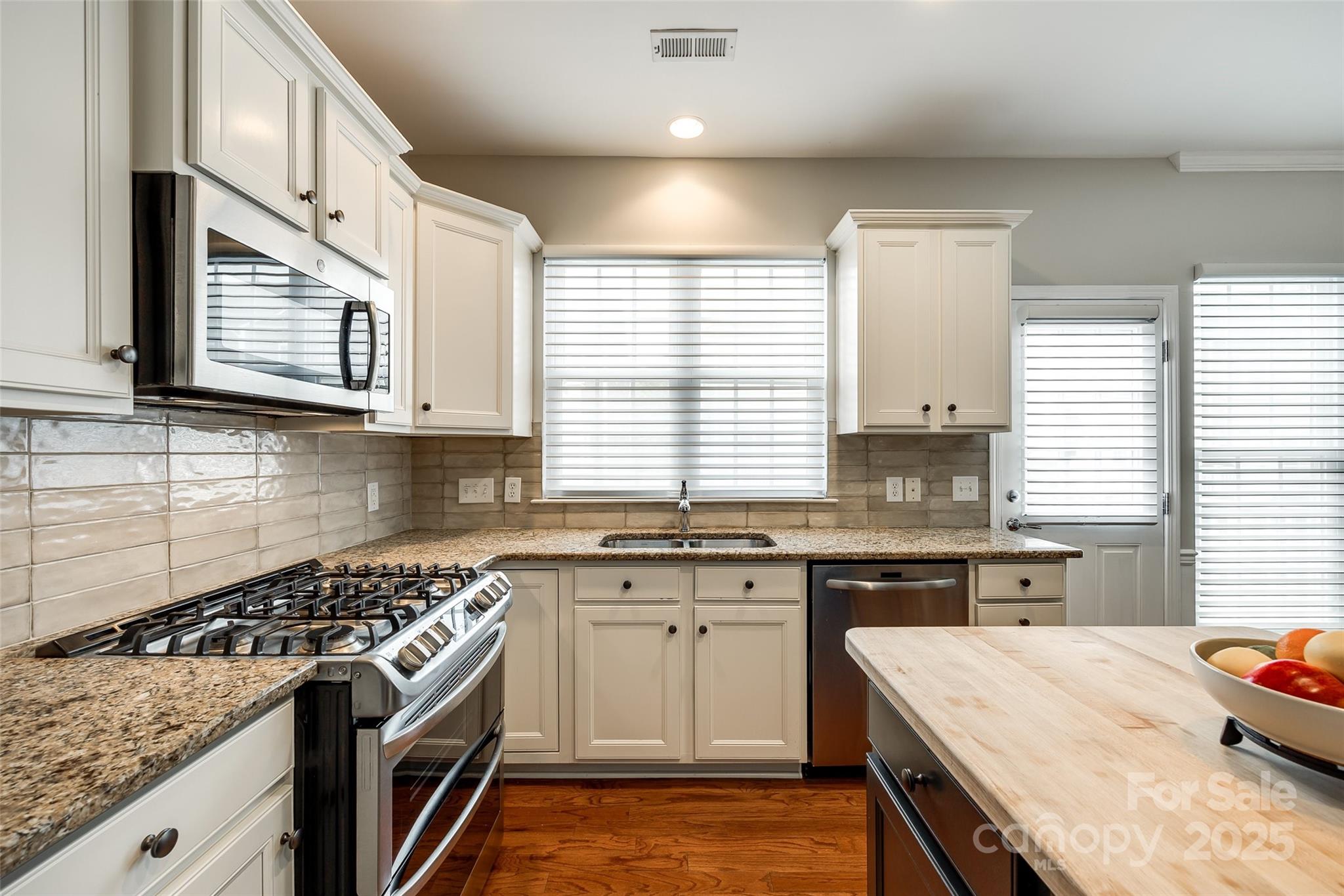 815 Granby Drive Fort Mill, SC 29708 - Photo 13 of 30 a kitchen with stainless steel appliances granite countertop a stove a sink dishwasher and white cabinets with wooden floor