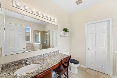 a bathroom with a granite countertop sink a mirror and a shower