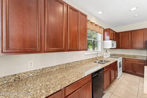 a kitchen with a sink and a stove top oven with wooden floor
