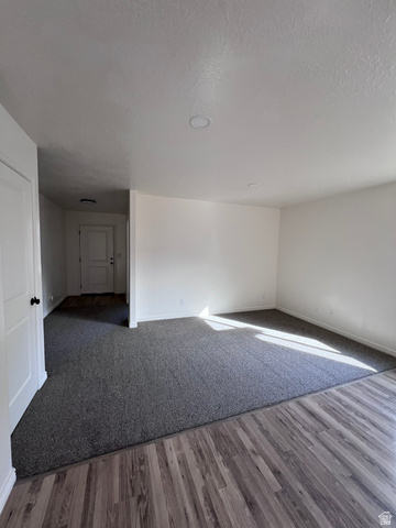1696 South Longview Road Santaquin, UT 84655 - Photo 8 of 16 Spare room with dark wood-type flooring, a textured ceiling, and dark colored carpet