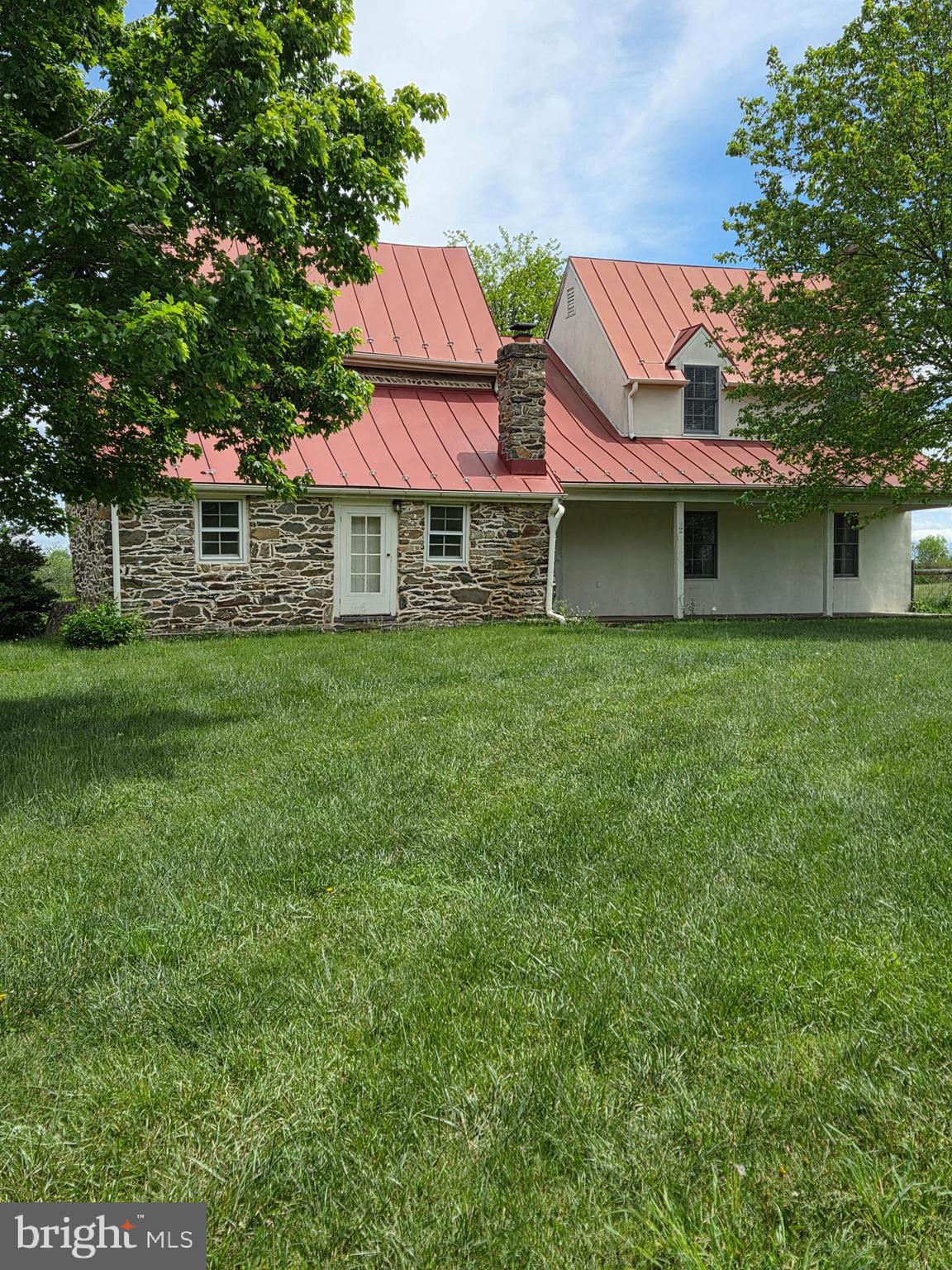 a view of a house with a yard and a large tree